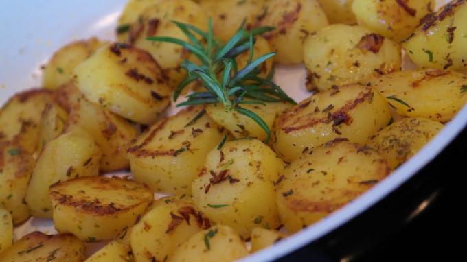Hoe de aardappelen met uien, komijn en rozemarijn bak