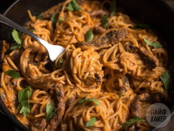 Pasta met rundvlees in tomatenroomsaus, geserveerd bestrooid met peterselie en peper