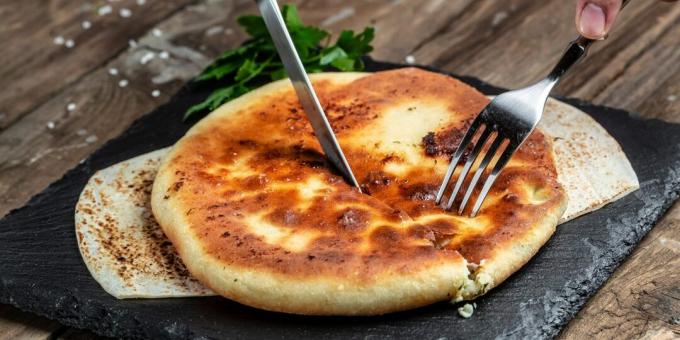 Dun deeg en veel toppings. Taart met aardappelen en kaas in een pan