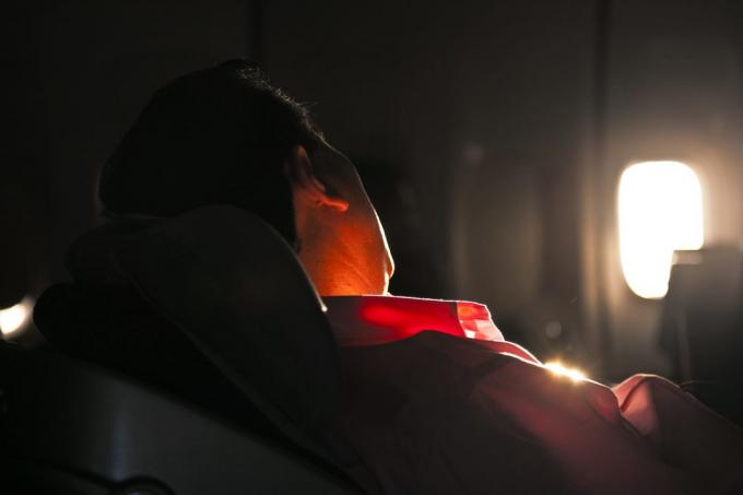 man slapen in de zetel van een vliegtuig in zonsopgang